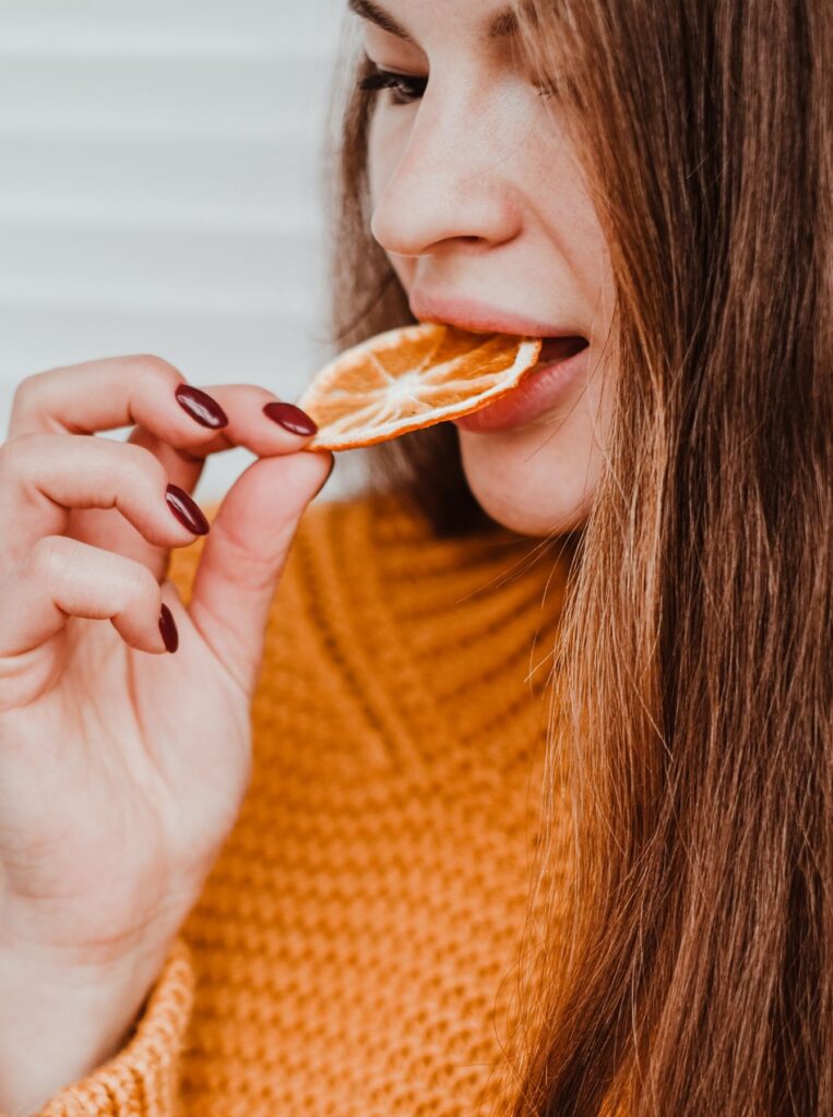 woman eating orange to boost her collagen productions