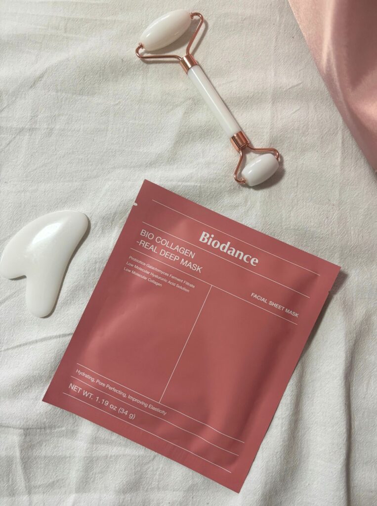 biodance sheet mask, jade roller, and gua sha on bed