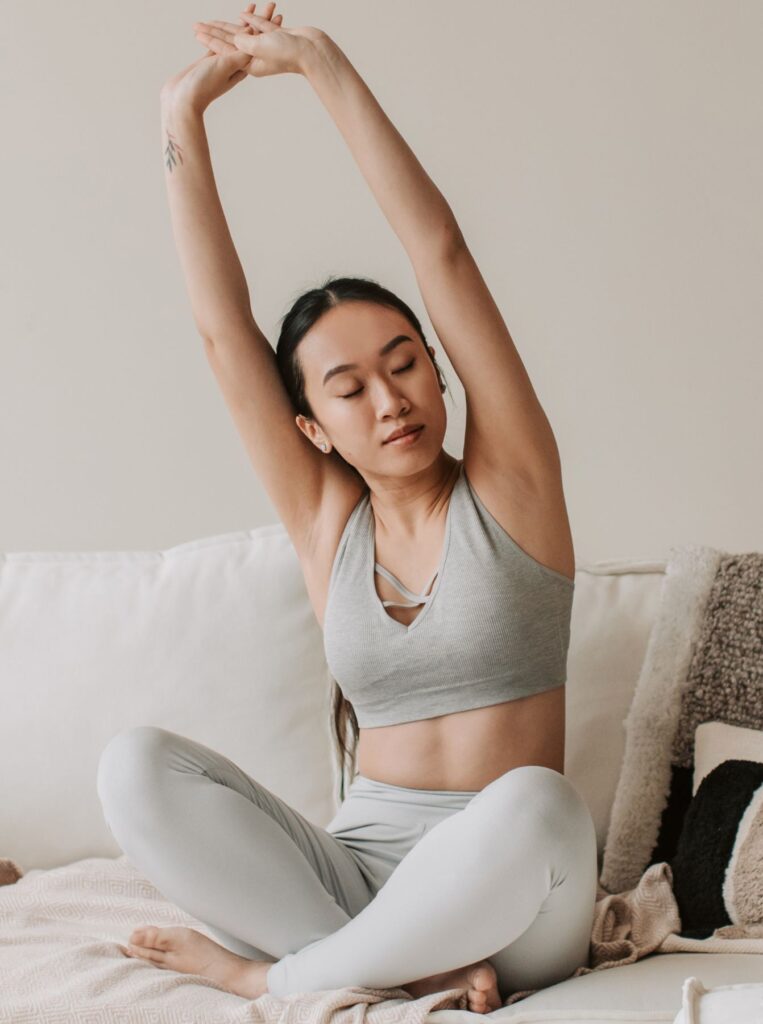 woman wearing workout clothes stretching in bed