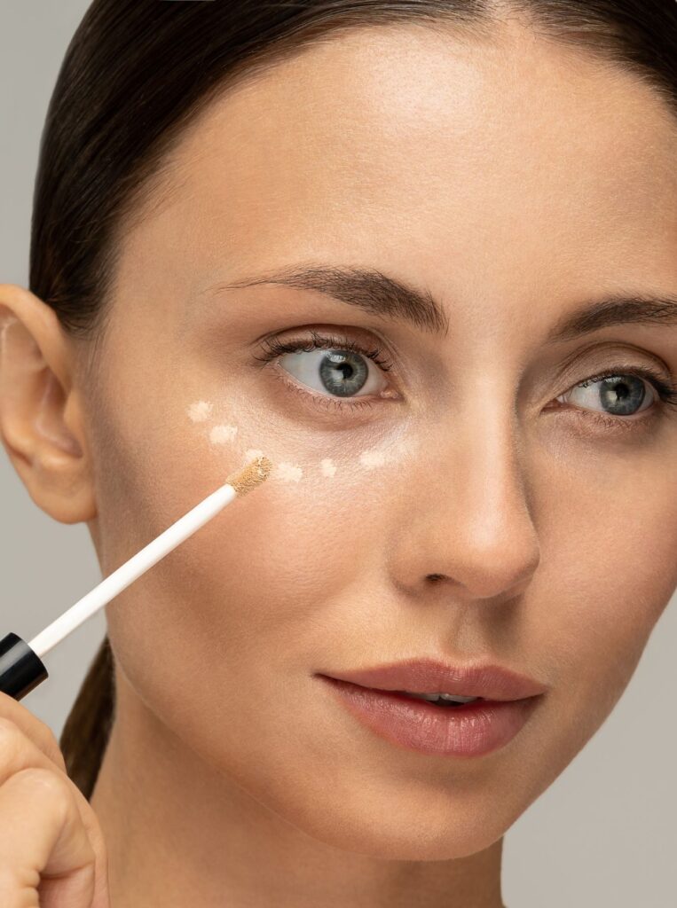 woman applying concealer under eyes