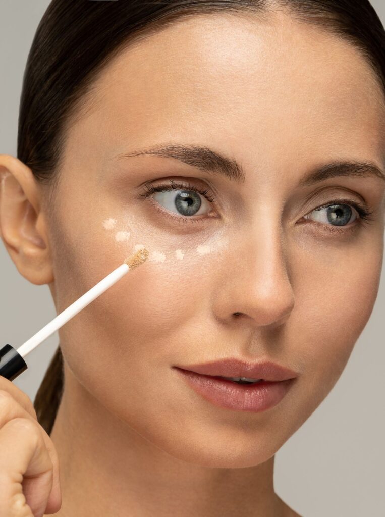 woman applying concealer in dots under eyes