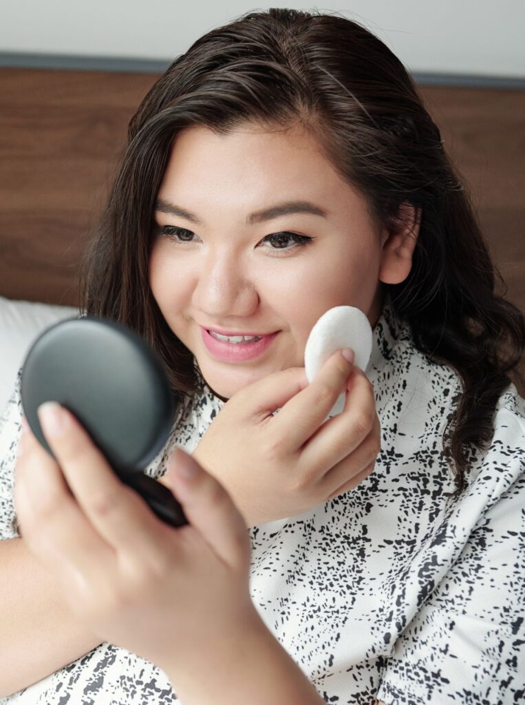 smiling woman applying powder on top of makeup 