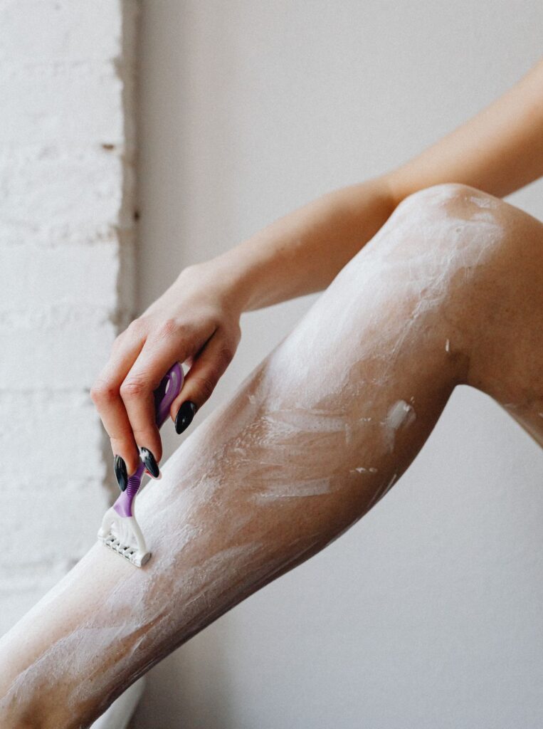 shaving legs with purple razor on top of cream