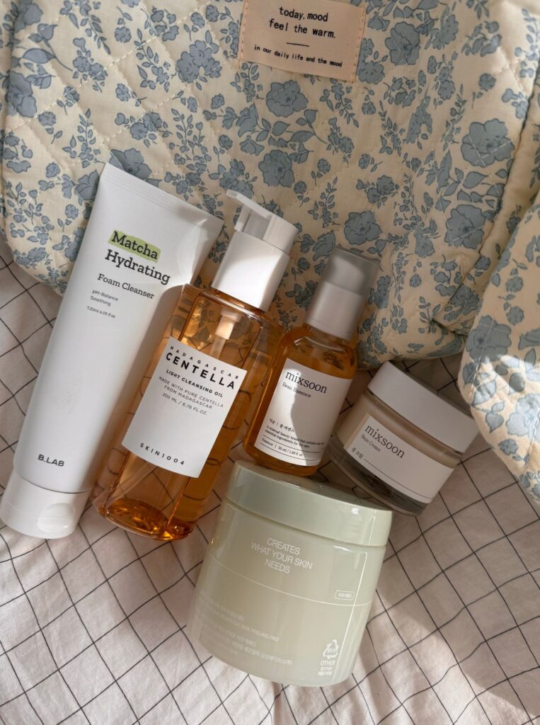 skincare products next to be a floral bag on bed
